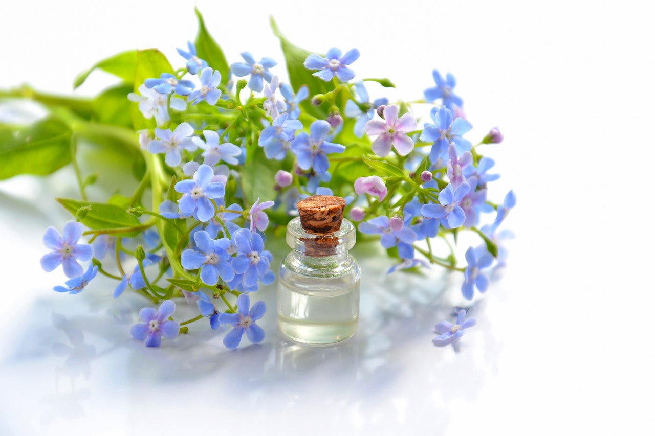 a glass bottle and purple flowers